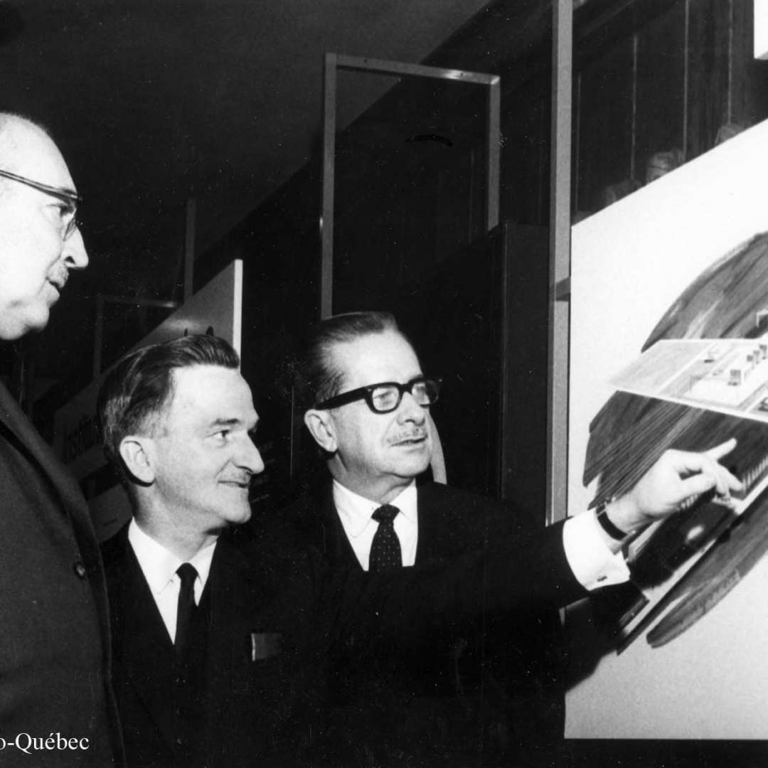<p>Présentation par Lionel Boulet de l’esquisse du projet de construction de l’Institut de recherche en électricité du Québec (l’IREQ) au président </p>
<p>d’Hydro‑Québec, Jean‑Claude Lessard, et au premier ministre du Québec, Daniel Johnson, 1967.</p>
<p>©Archives d’Hydro‑Québec</p>
