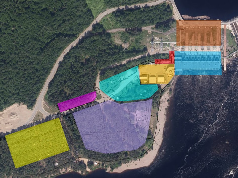 Vue aérienne de l’aménagement hydroélectrique de la Trenche. On peut y voir les zones suivantes: le stationnement principal, l’aire de travail, les aires réservées aux fournisseurs, les roulottes de chantier, l’aire de manœuvre et les bâtiments de l’exploitant, le bâtiment modulaire pour travailleurs, la prise d’eau et les conduites forcées, la centrale et les compartiments des transformateurs.