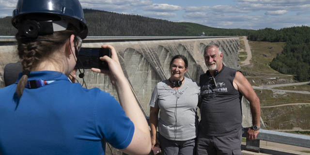 A couple has their photo taken in front of Daniel-Johnson dam.