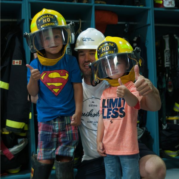 A father with his children wearing firefighter helmets.