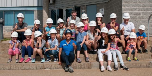 A tour guide and a school group outside Îles-de-la-Madeleine generating station.