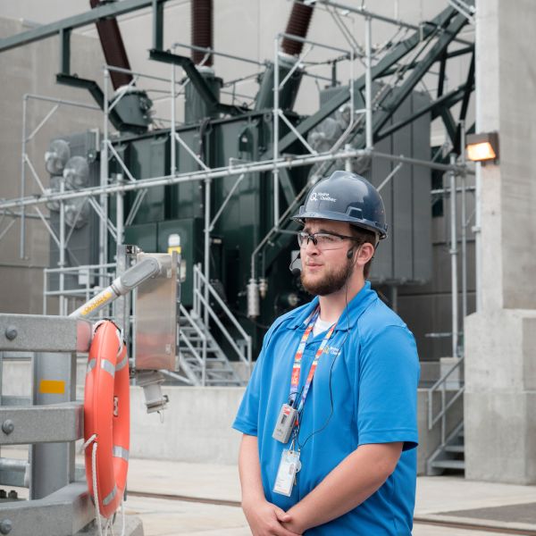 A tour guide in front of a transformer at Romaine-1 generating station.